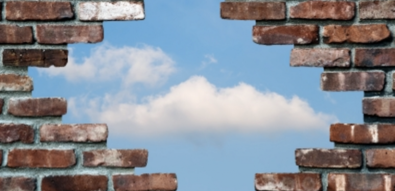 brick wall broken through to blue sky