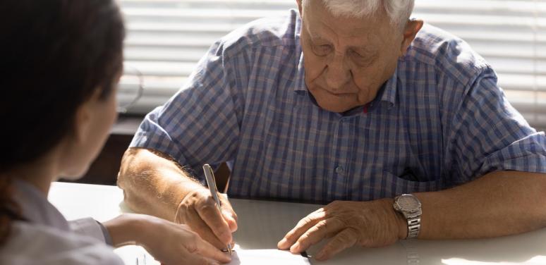 old man signing paper